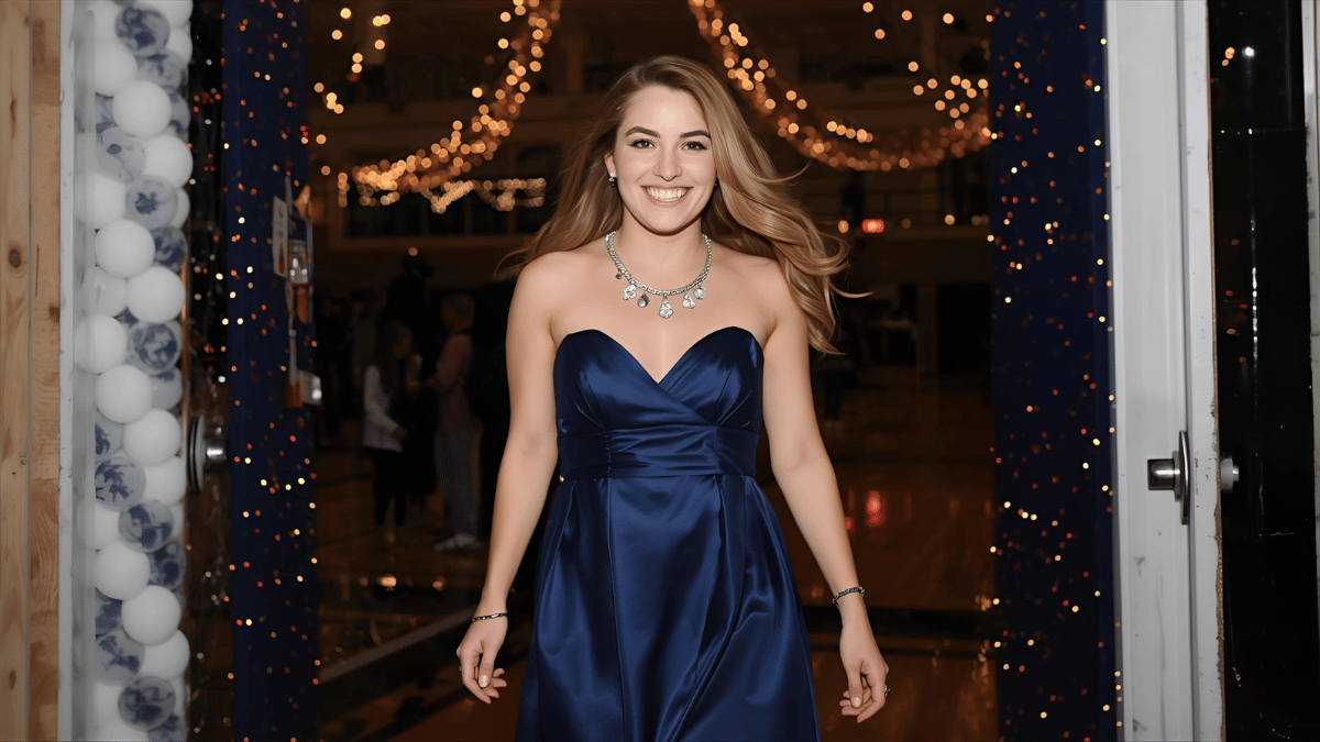 A confident young woman walking into a decorated school gym in a navy satin homecoming dress, smiling brightly with friends as lights twinkle in the background.